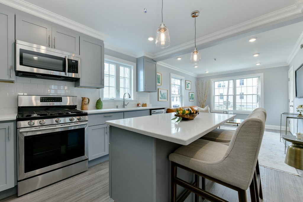 a kitchen with stainless steel appliances a stove a sink a microwave a dining table and chairs