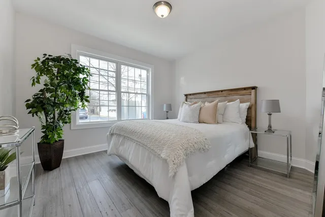 a bed sitting in a bedroom next to a window and a potted plant