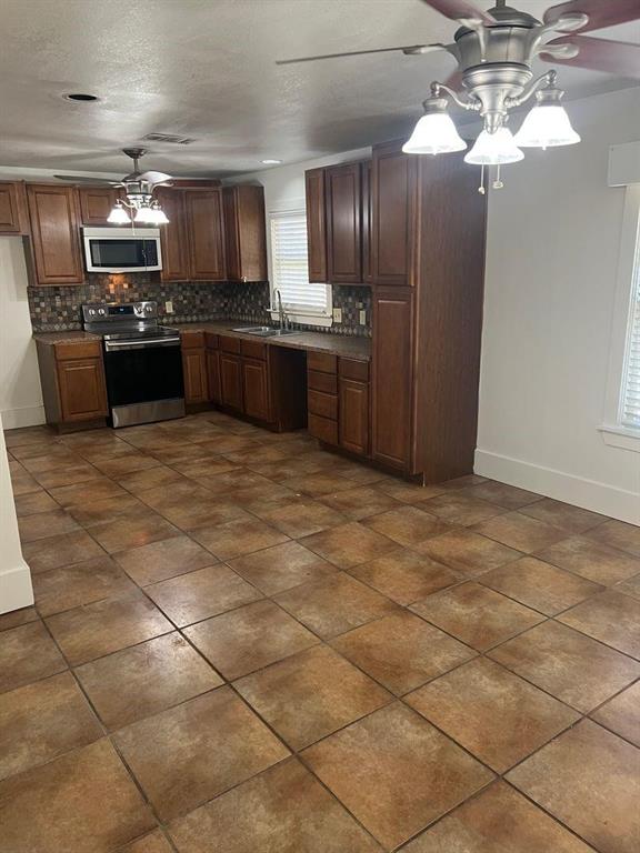 1209 Bawcom Street Sweetwater, TX 79556 - Photo 4 of 10 a kitchen with stainless steel appliances granite countertop a sink a stove top oven and cabinets