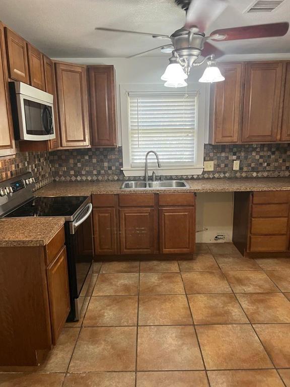 1209 Bawcom Street Sweetwater, TX 79556 - Photo 5 of 10 a kitchen with a sink a stove top oven and cabinets