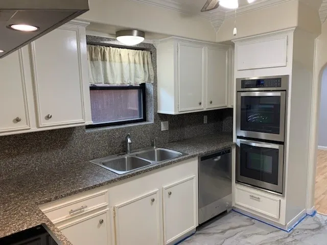 a kitchen with granite countertop white cabinets and stainless steel appliances