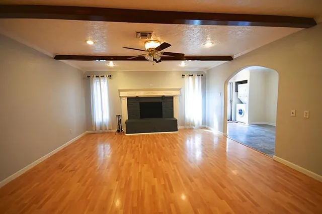 a view of an empty room with wooden floor and a fireplace