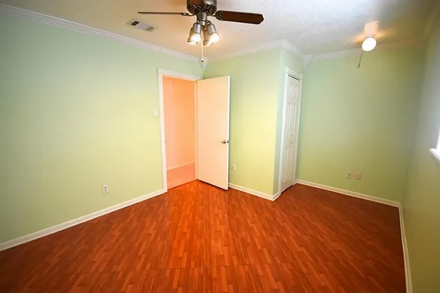 an empty room with wooden floor fan and windows