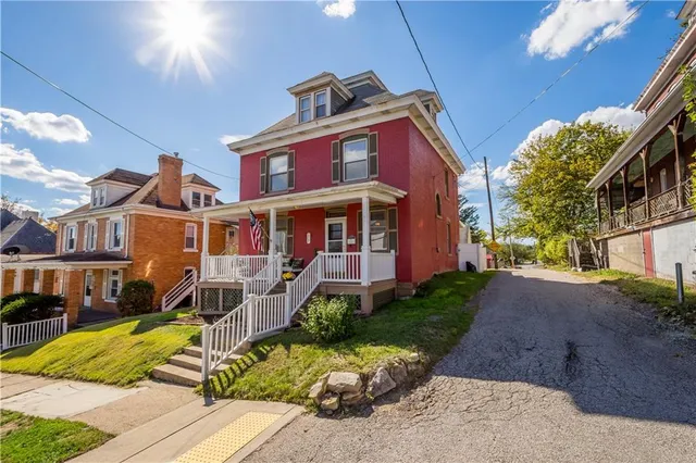 a front view of a house with a yard outdoor seating and covered with trees