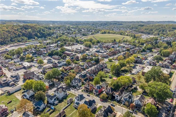 an aerial view of residential houses with outdoor space and trees