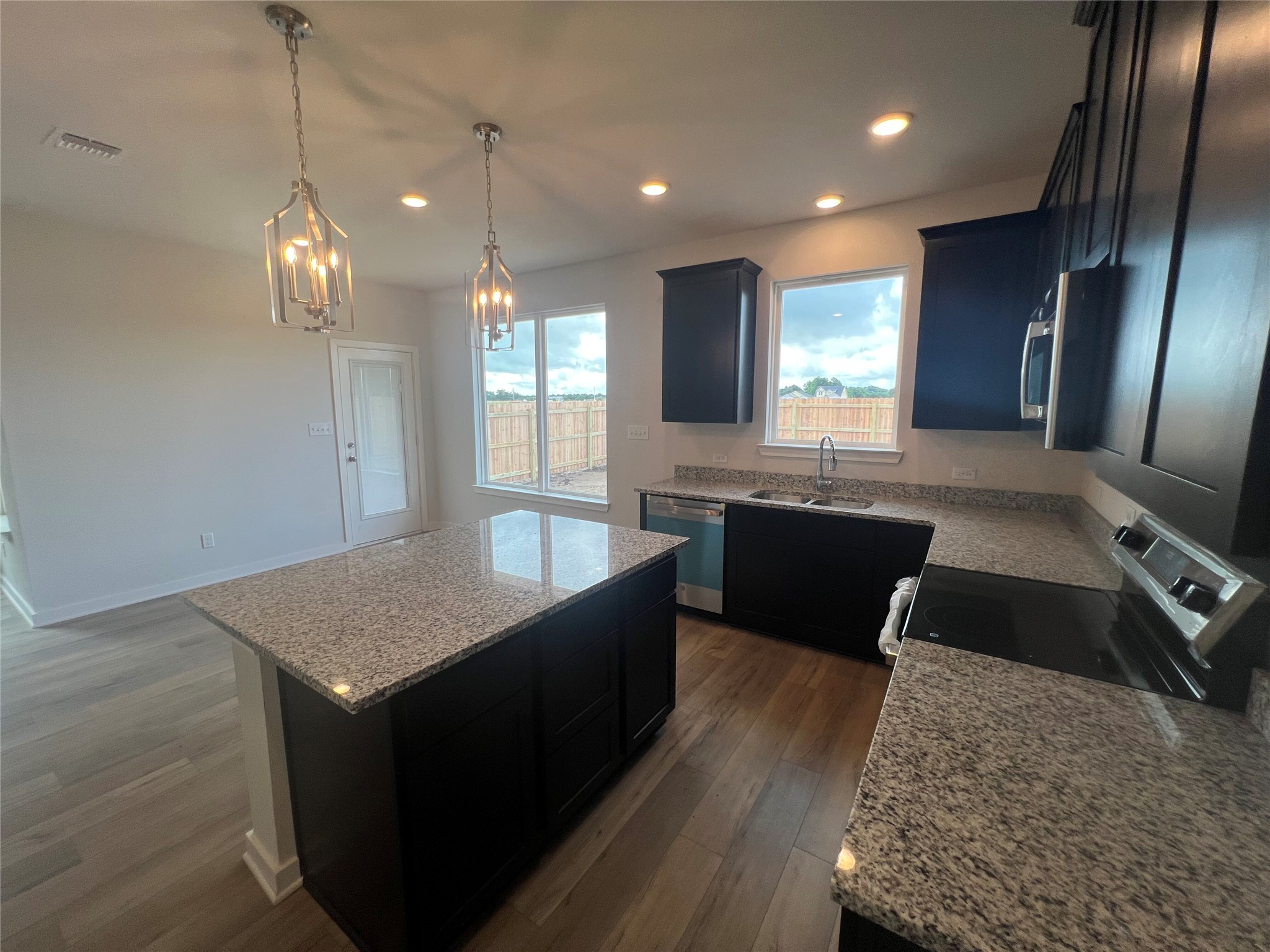 255 Gus Loop Georgetown, TX 78626 - Photo 15 of 24 Elegant pendant lighting illuminates a modern kitchen featuring rich cabinetry and durable granite countertops.
