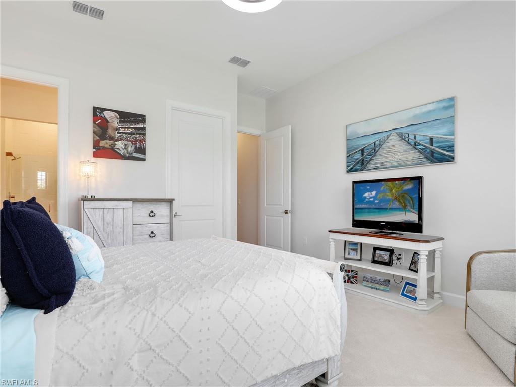 18412 Ridgeline Drive Estero, FL 33928 - Photo 33 of 50 a bedroom with a bed a couch and a flat screen tv