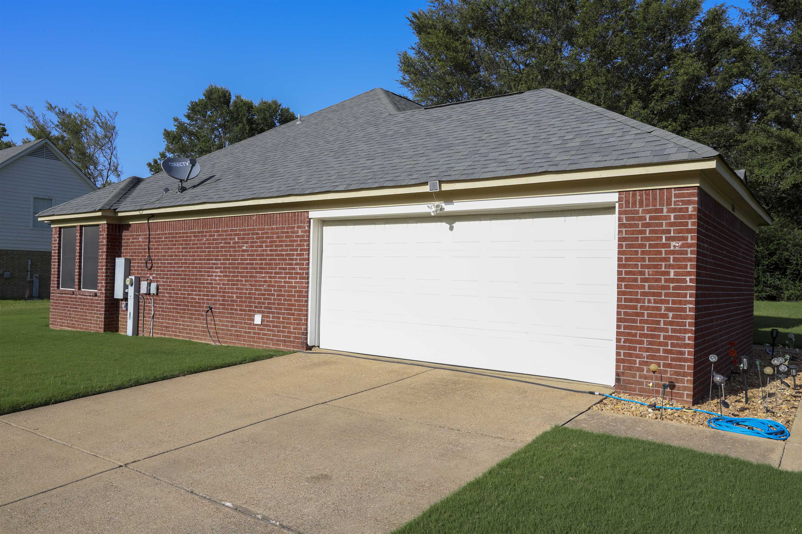 6626 Finch Road Memphis, TN 38141 - Photo 2 of 14 Brick exterior with a gray asphalt shingle roof, integrated garage, concrete driveway, and established lawn