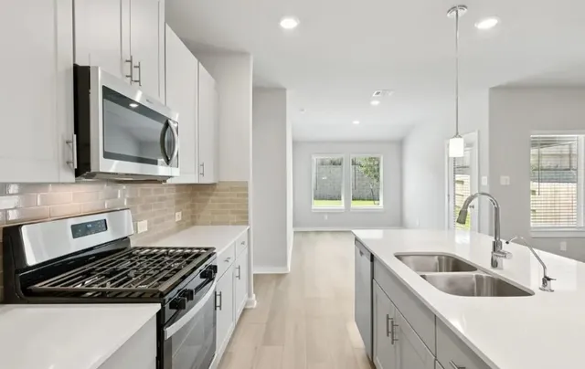 a kitchen that has a sink and a stove top oven with wooden floor