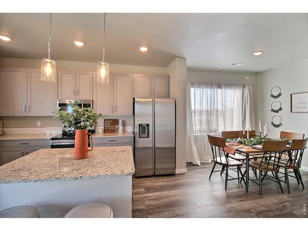 a kitchen with stainless steel appliances granite countertop sink refrigerator dining table and chairs