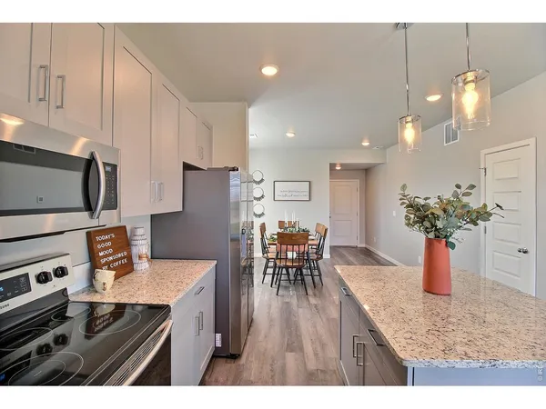 a kitchen with stainless steel appliances granite countertop a dining table chairs and white cabinets