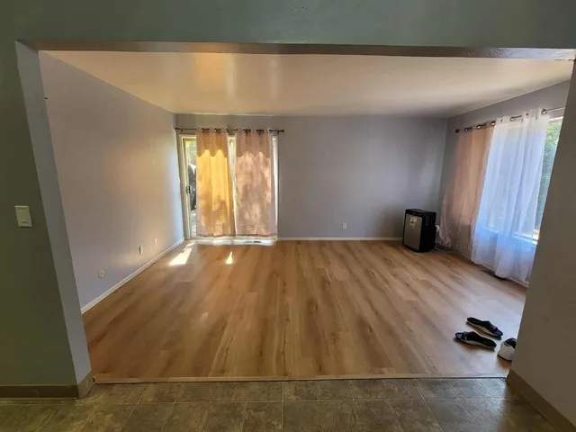 an empty room with wooden floor and windows