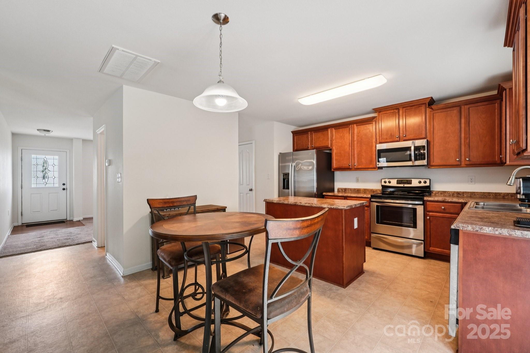 2289 Reid Pointe Avenue Indian Land, SC 29707 - Photo 7 of 39 a kitchen with stainless steel appliances granite countertop a stove top oven a sink dishwasher a dining table and chairs with wooden floor