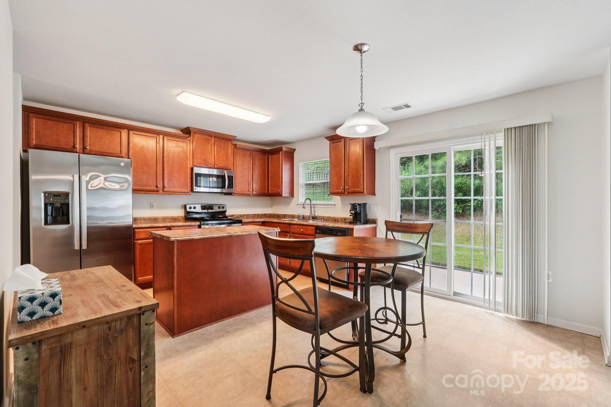 2289 Reid Pointe Avenue Indian Land, SC 29707 - Photo 9 of 39 a kitchen with stainless steel appliances granite countertop a stove top oven a refrigerator a sink dishwasher with a dining table and chairs with wooden floor