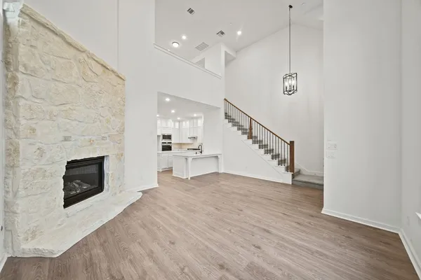 a view of a kitchen and an empty room with wooden floor