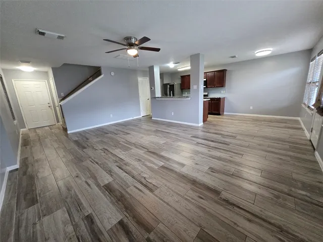 an empty room with wooden floor and windows
