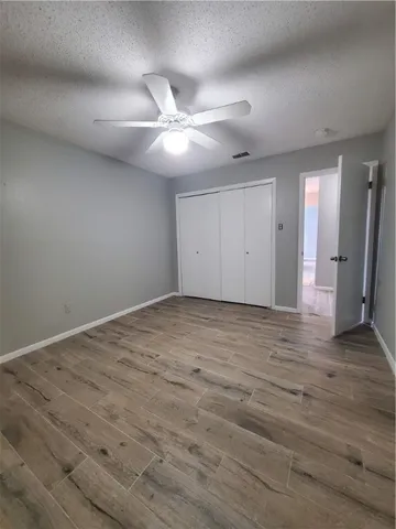 an empty room with wooden floor and fan
