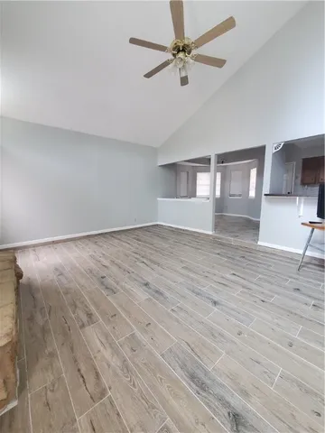 an empty room with wooden floor ceiling fan and windows
