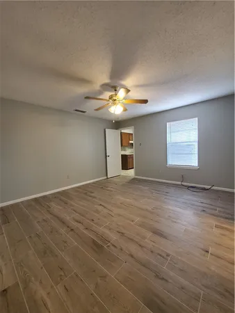 an empty room with a chandelier fan and windows