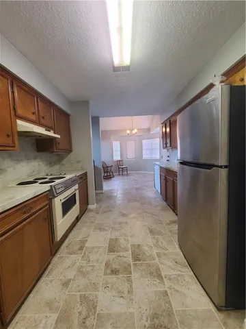 a kitchen with granite countertop a refrigerator and a stove top oven
