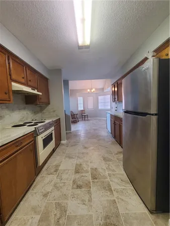 a kitchen with granite countertop a refrigerator and a stove top oven