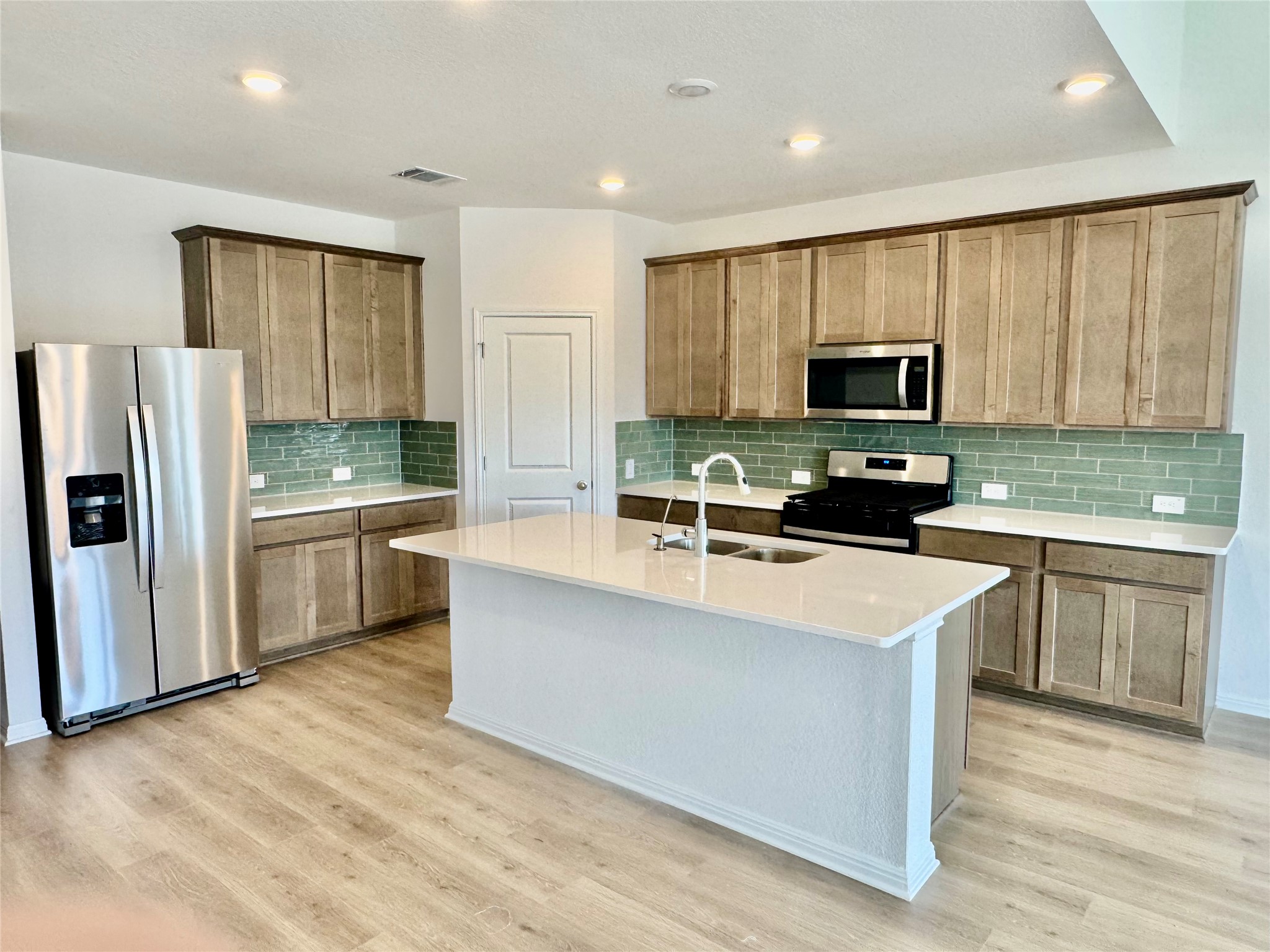 163 Pendleton Drive Kyle, TX 78640 - Photo 2 of 15 a kitchen with stainless steel appliances a microwave a stove a sink dishwasher a refrigerator and white cabinets with wooden floor
