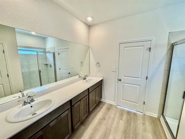 a spacious bathroom with a double vanity sink a mirror and a shower