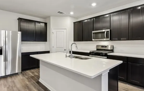 a kitchen with kitchen island a counter space a sink appliances and cabinets