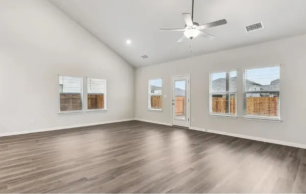 a view of an empty room with window and wooden floor