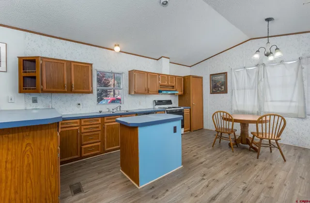 a kitchen with stainless steel appliances granite countertop a kitchen island hardwood floor sink stove dining table and chairs