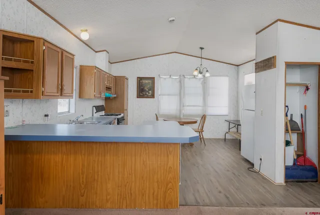 a view of a kitchen with kitchen island a sink wooden floor and stainless steel appliances