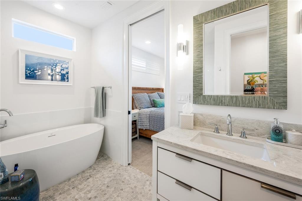 4129 Willowhead Way Naples, FL 34103 - Photo 35 of 50 a bathroom with a granite countertop tub a sink and a large mirror