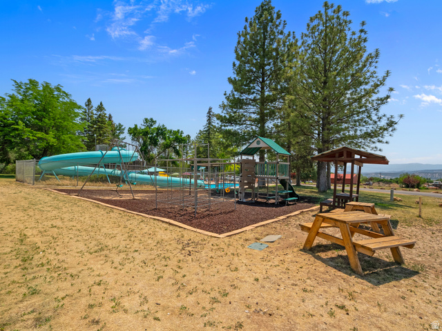22630 Spring View Drive Fairview, UT 84629 - Photo 26 of 32 Outdoor recreational area featuring a large blue water slide, a structured play system with a green roof, a shaded picnic table, and additional wooden seating