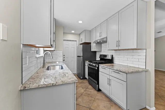 a kitchen with stainless steel appliances granite countertop a sink stove and refrigerator