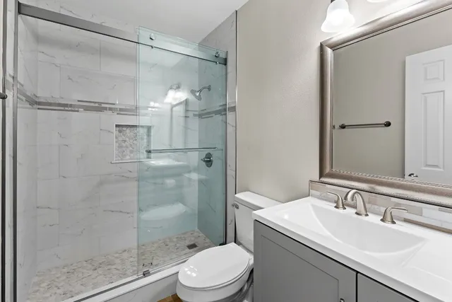 a bathroom with a sink vanity granite toilet and shower