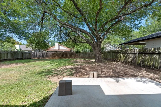 a view of backyard with wooden fence and large trees