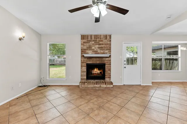 a view of an empty room with window and chandelier fan