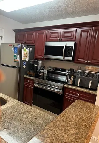 a kitchen with stainless steel appliances kitchen island granite countertop a stove and a sink