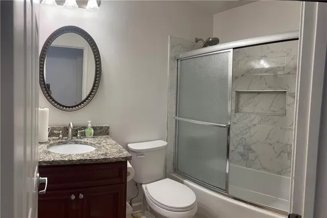 a bathroom with a granite countertop sink toilet and a mirror