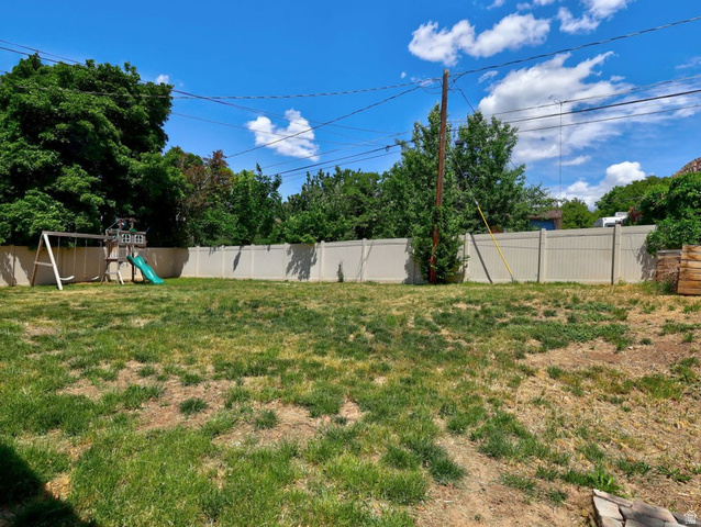 1272 Cook Street Ogden, UT 84404 - Photo 51 of 58 Expansive lawn area featuring a full perimeter fence, mature trees, and clear sky