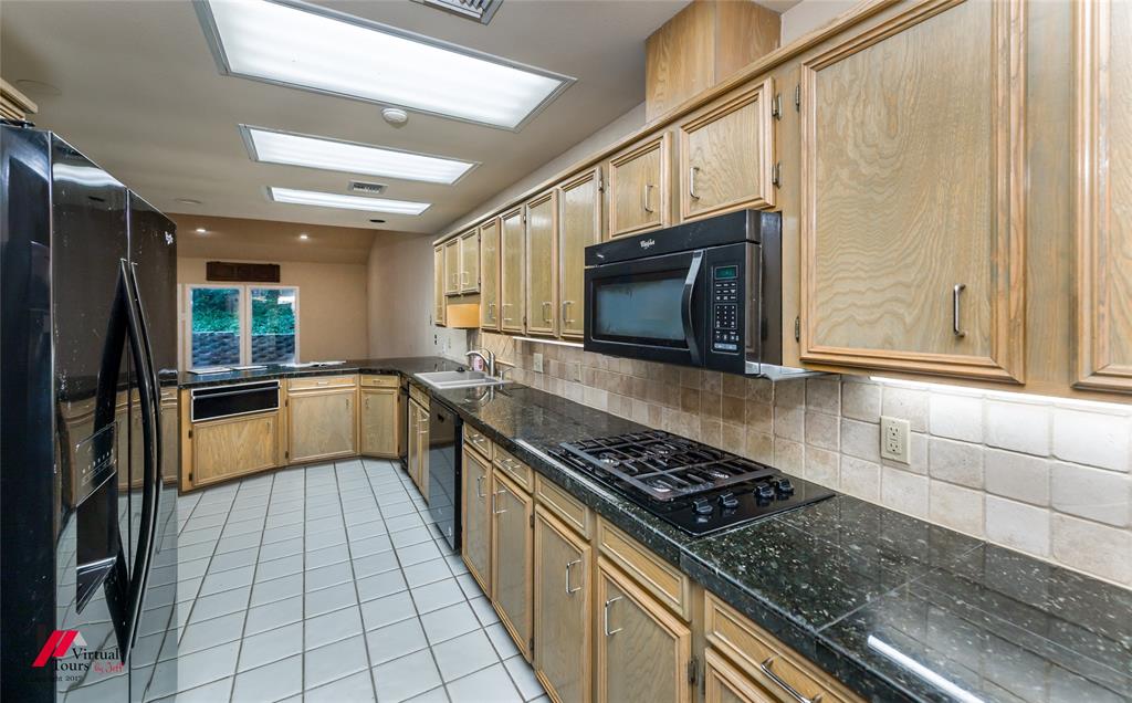 300 Pierremont Road, Unit 40 Shreveport, LA 71106 - Photo 15 of 34 U-shaped kitchen featuring wood-finish cabinetry, dark speckled countertops, a tile backsplash, and white square tile flooring