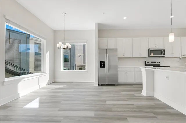 a view of a kitchen with a refrigerator a stove top oven and a wooden floor