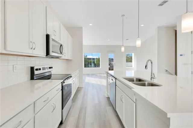 a kitchen with white cabinets sink and stainless steel appliances