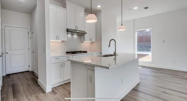 a kitchen with stainless steel appliances kitchen island wooden floors and white cabinets