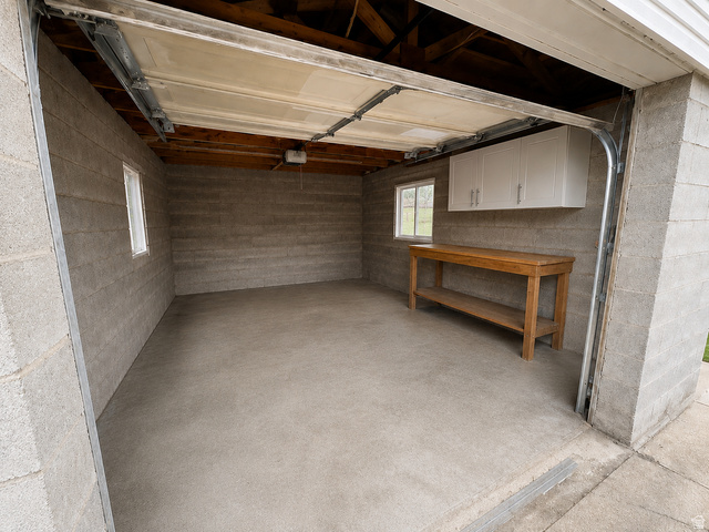 1791 West 170 South, Unit 8 Provo, UT 84601 - Photo 24 of 25 Spacious garage featuring a concrete block interior, exposed ceiling joists, two windows with white trim, and a concrete floor