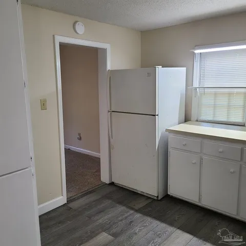a kitchen with white cabinets and a stove with wooden floor
