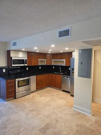 a large kitchen with kitchen island granite countertop a stove top oven a sink a counter space and cabinets