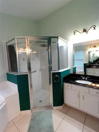 a bathroom with a granite countertop sink a mirror and shower