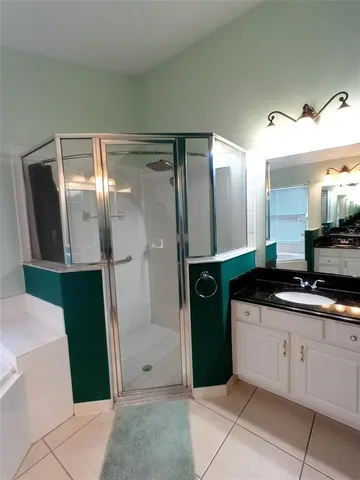a bathroom with a granite countertop sink a mirror and shower