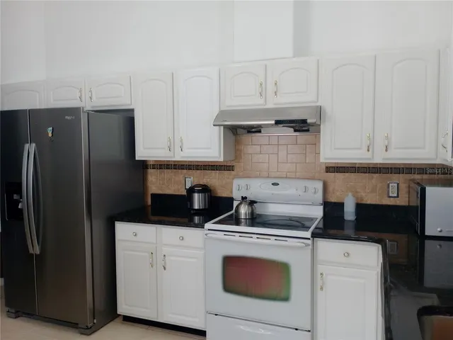 a kitchen with stainless steel appliances granite countertop white cabinets and a refrigerator